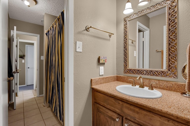 full bath with tile patterned floors, a textured wall, a textured ceiling, and vanity