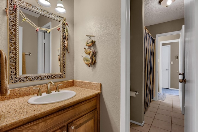 bathroom with tile patterned flooring, baseboards, a textured ceiling, and vanity