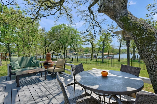 view of patio / terrace featuring outdoor dining space, a deck with water view, fence, and an outdoor living space