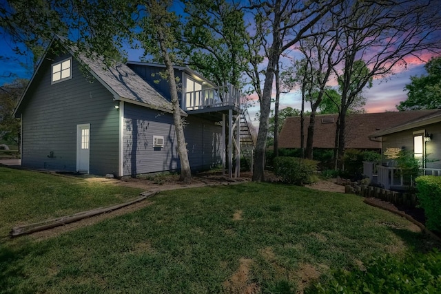 back of property at dusk featuring a deck, a yard, and stairway