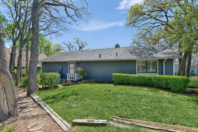 view of front facade featuring roof with shingles, a chimney, and a front lawn