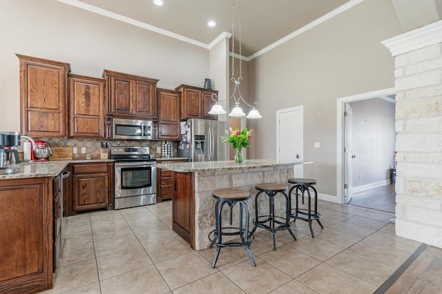 kitchen with a breakfast bar, a kitchen island, ornamental molding, appliances with stainless steel finishes, and decorative backsplash