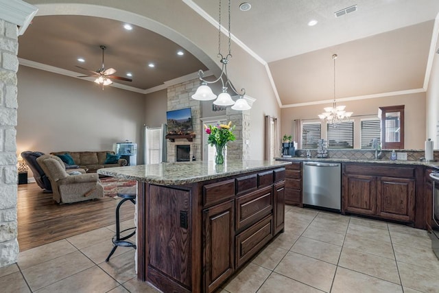 kitchen featuring light tile patterned floors, a stone fireplace, ceiling fan with notable chandelier, dishwasher, and crown molding