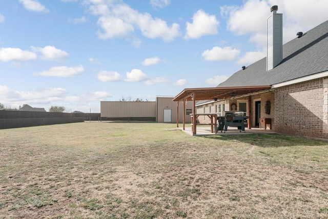 view of yard featuring a pole building, a patio, an outdoor structure, and fence