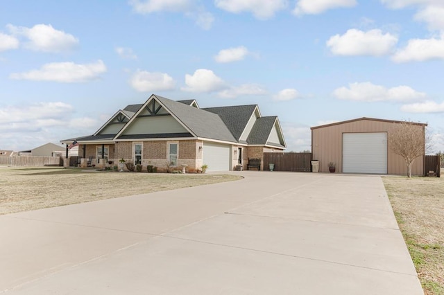 view of front facade featuring an outbuilding, brick siding, concrete driveway, a front yard, and fence