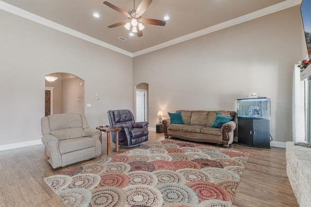 living area with arched walkways, ornamental molding, wood finished floors, and baseboards