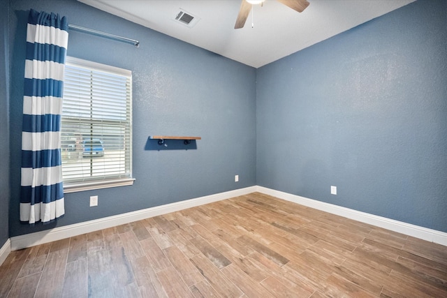 empty room with baseboards, wood finished floors, visible vents, and ceiling fan