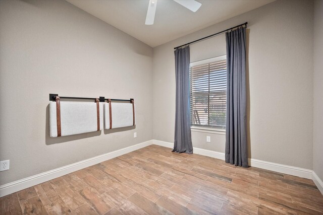 unfurnished room featuring lofted ceiling, wood finished floors, a ceiling fan, and baseboards