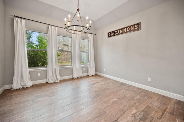 unfurnished dining area featuring vaulted ceiling, wood finished floors, baseboards, and a notable chandelier