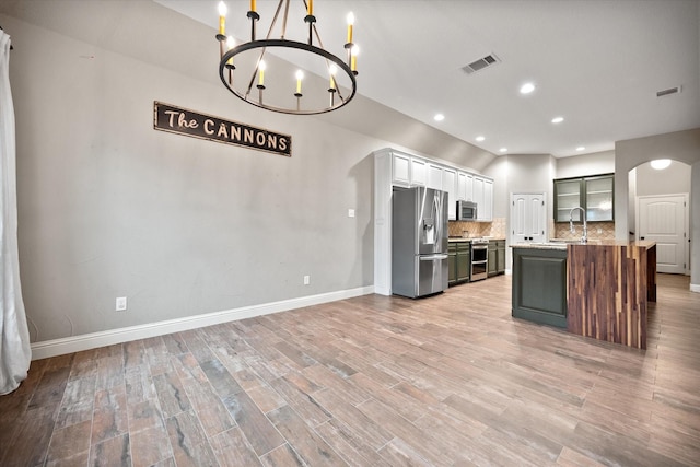 kitchen featuring arched walkways, visible vents, decorative backsplash, light countertops, and appliances with stainless steel finishes