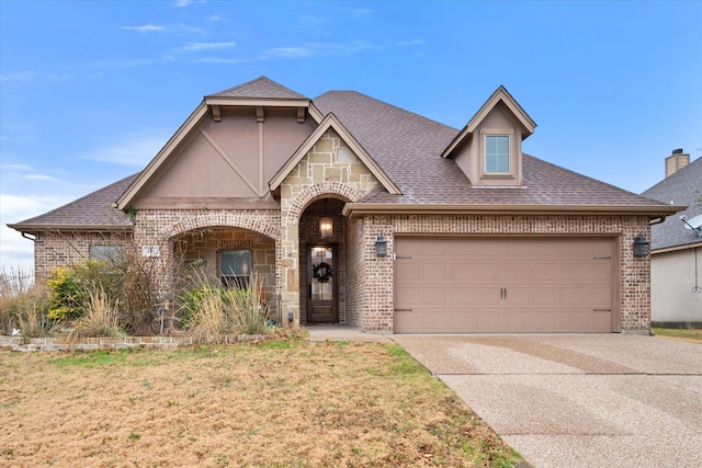 view of front of house with driveway, brick siding, roof with shingles, an attached garage, and a front yard