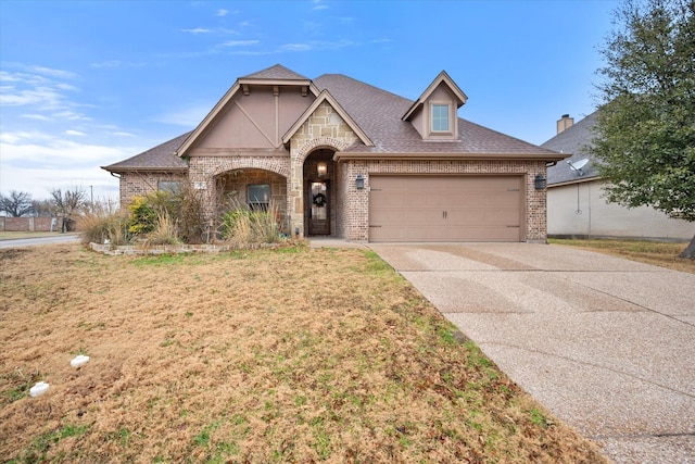french country style house featuring concrete driveway, brick siding, roof with shingles, and a garage