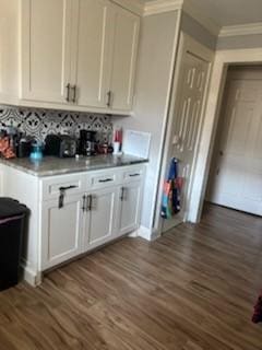 bar featuring tasteful backsplash, ornamental molding, and dark wood finished floors