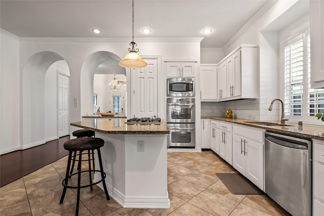 kitchen with appliances with stainless steel finishes, dark stone counters, and white cabinets