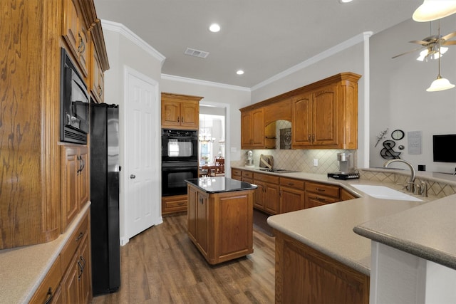 kitchen featuring visible vents, a center island, a peninsula, black appliances, and a sink