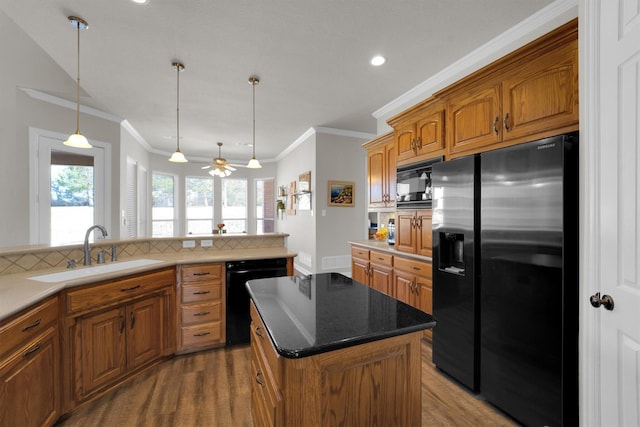 kitchen with a kitchen island, brown cabinets, backsplash, black appliances, and a sink