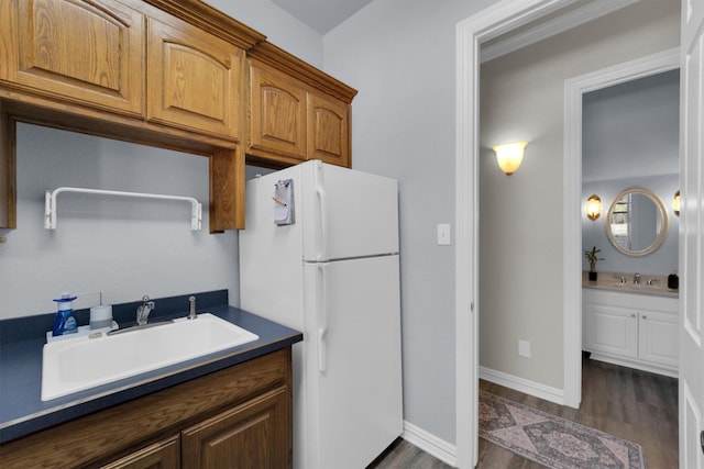 kitchen with dark wood-style floors, dark countertops, a sink, and freestanding refrigerator