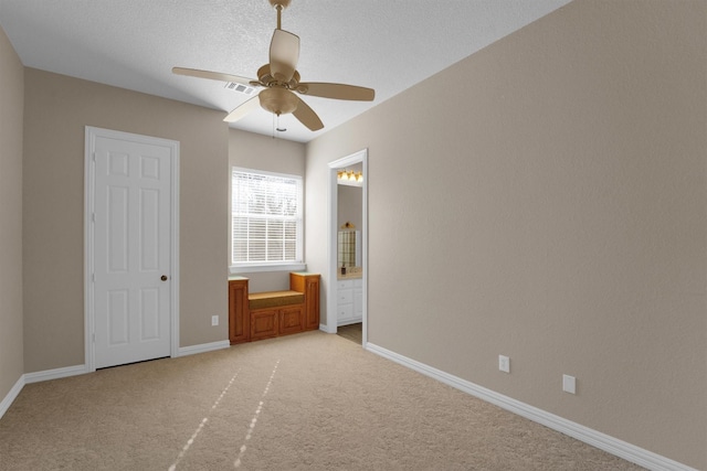 unfurnished bedroom with light carpet, baseboards, a ceiling fan, and ensuite bathroom