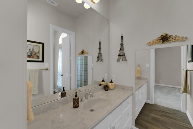 bathroom featuring baseboards, visible vents, wood finished floors, and vanity