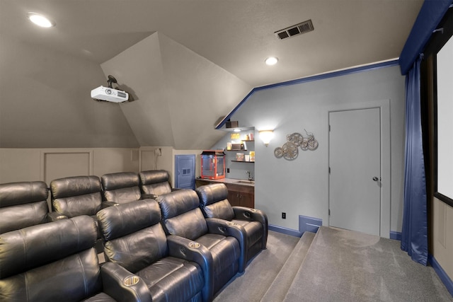 carpeted cinema room featuring lofted ceiling, baseboards, visible vents, and a sink