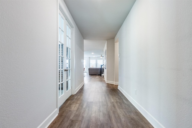 hall with dark wood-type flooring, french doors, a textured wall, and baseboards