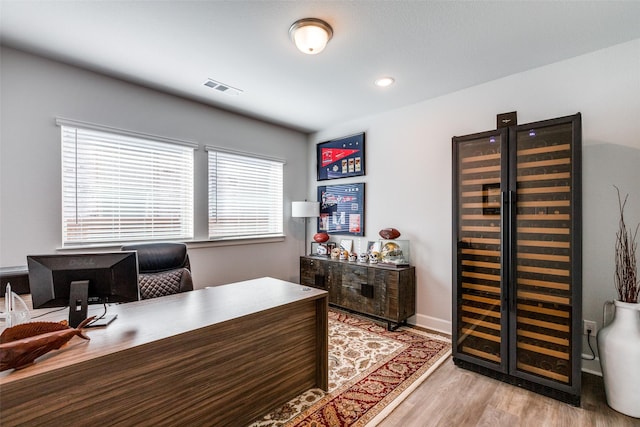 home office with light wood finished floors, recessed lighting, visible vents, beverage cooler, and baseboards