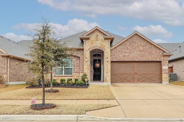 view of front of home featuring stone siding, roof with shingles, concrete driveway, and brick siding