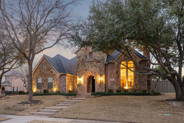 view of front facade with stone siding, stairs, and brick siding