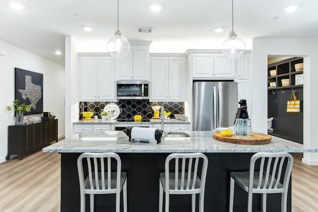 721 Prosper Ln, Wylie, TX 75098 - kitchen featuring backsplash, visible vents, light wood-type flooring, a sink, and stainless steel appliances