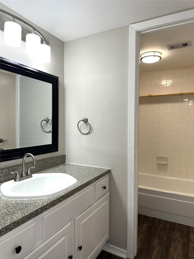 full bath with shower / washtub combination, visible vents, a textured wall, vanity, and wood finished floors