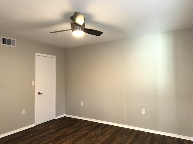 empty room with dark wood-style floors, visible vents, ceiling fan, and baseboards