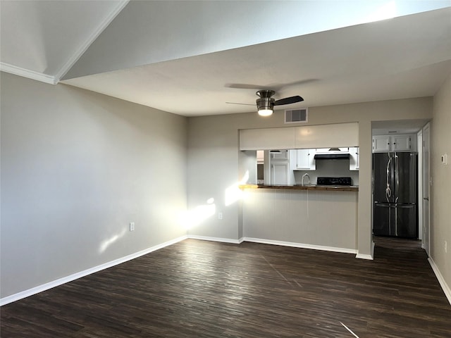 unfurnished living room featuring dark wood-style flooring, visible vents, a sink, ceiling fan, and baseboards