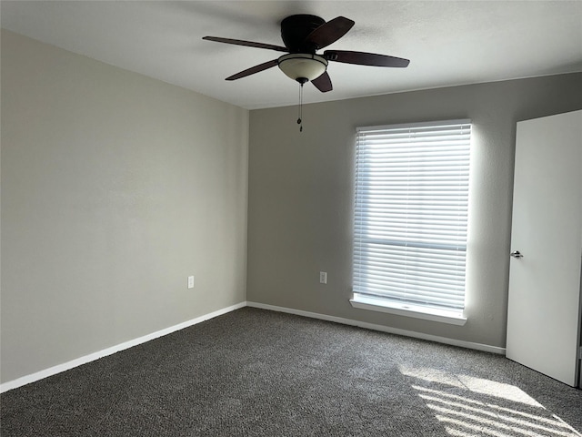 spare room with baseboards, dark colored carpet, and a ceiling fan