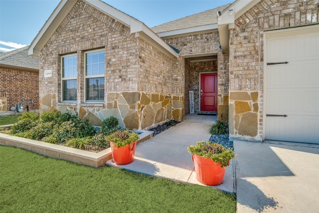 property entrance with stone siding, a shingled roof, and brick siding