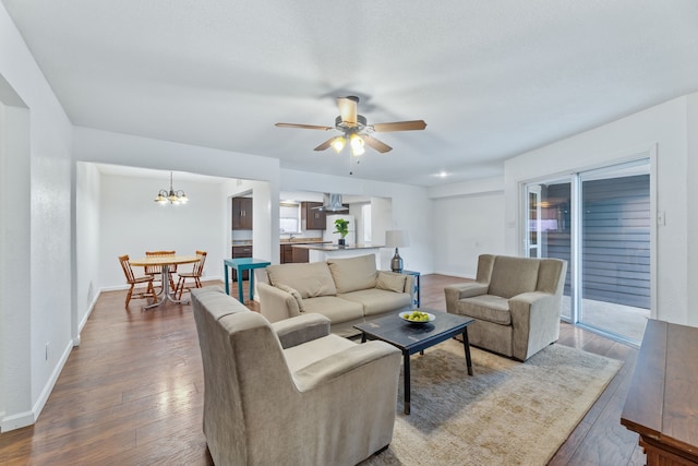 living area with baseboards, wood finished floors, and ceiling fan with notable chandelier