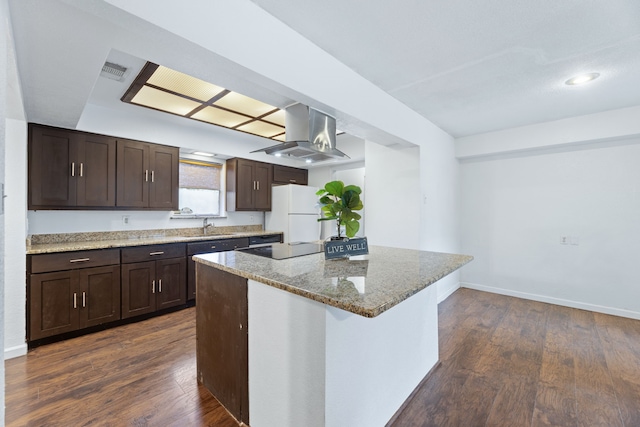 kitchen featuring a kitchen island, light stone counters, dark wood-type flooring, freestanding refrigerator, and a sink