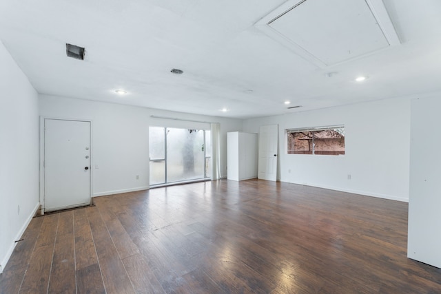 empty room featuring attic access, baseboards, dark wood finished floors, and recessed lighting