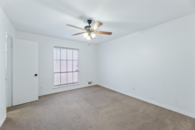 spare room with light carpet, ceiling fan, visible vents, and baseboards