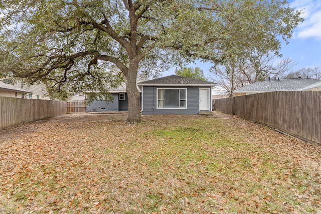 rear view of house with a yard and a fenced backyard