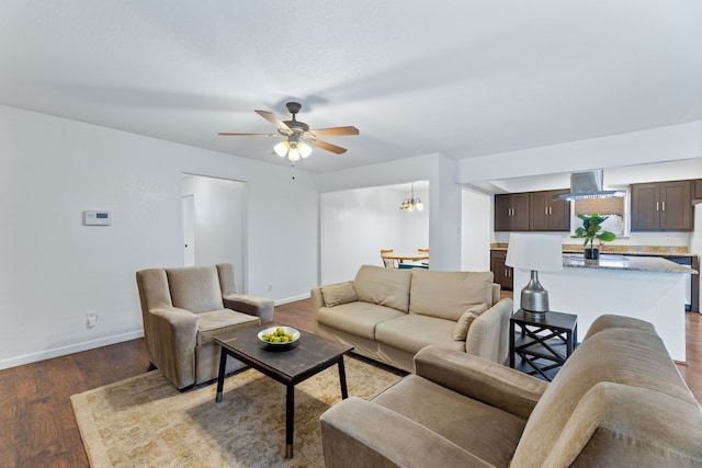 living area with ceiling fan with notable chandelier, baseboards, and wood finished floors