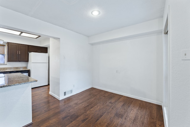 unfurnished dining area featuring dark wood finished floors, visible vents, and baseboards