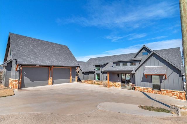 view of front facade with stone siding, concrete driveway, board and batten siding, and roof with shingles