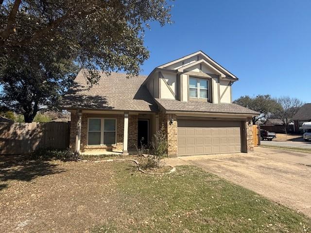 view of front of property with brick siding, driveway, an attached garage, and fence