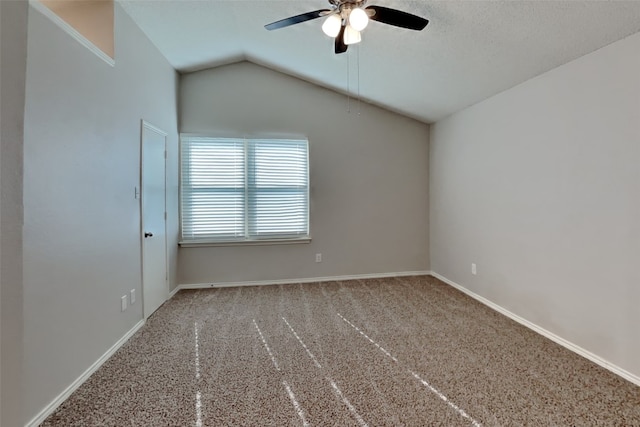 spare room featuring carpet flooring, vaulted ceiling, baseboards, and ceiling fan