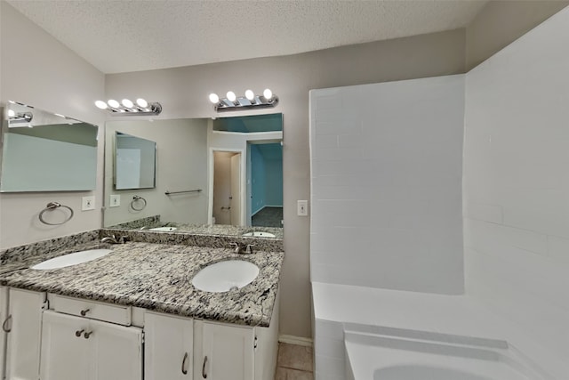 full bathroom with a sink, a textured ceiling, and a bath