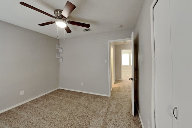 unfurnished bedroom featuring light colored carpet, visible vents, attic access, a textured ceiling, and baseboards