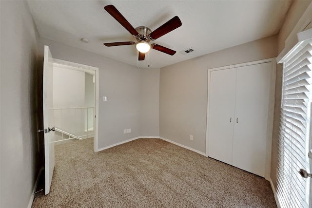 unfurnished bedroom with baseboards, visible vents, a ceiling fan, carpet flooring, and a closet