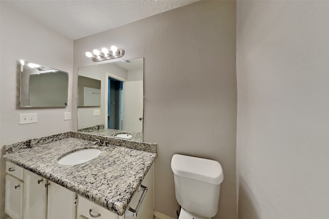 bathroom with toilet, a textured ceiling, and vanity