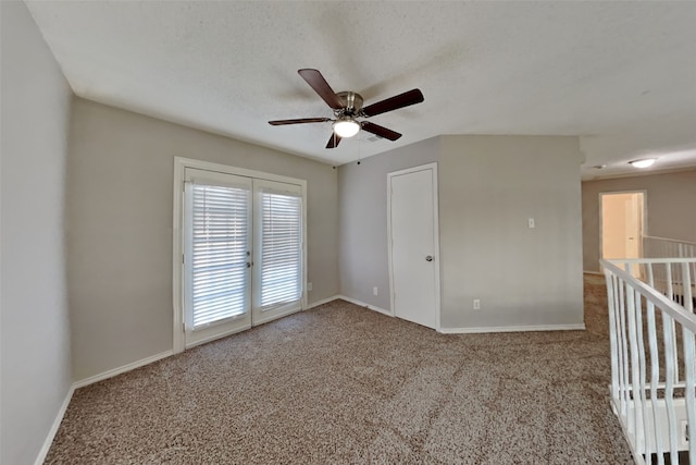 carpeted spare room featuring ceiling fan, a textured ceiling, and baseboards