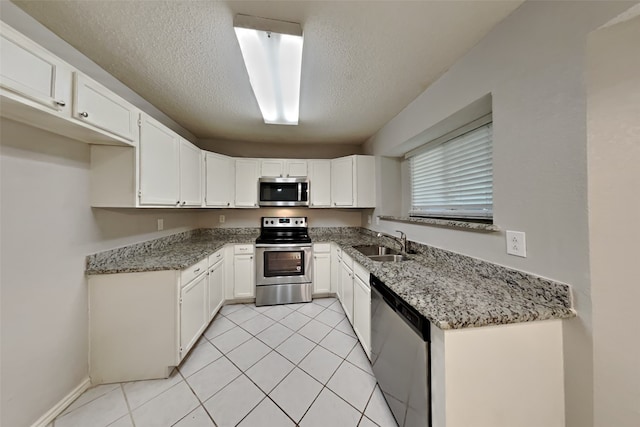 kitchen with white cabinets, a textured ceiling, stainless steel appliances, and a sink